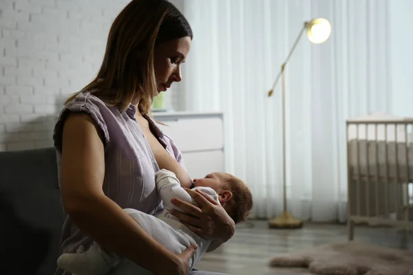 年轻妇女在家里用母乳喂她的小宝宝 案文的篇幅 — 图库照片