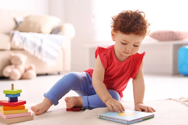 Симпатичный маленький ребенок играет с игрушками на полу дома — стоковое фото