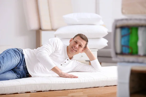 Man testing soft mattress in furniture store — Stock Photo, Image