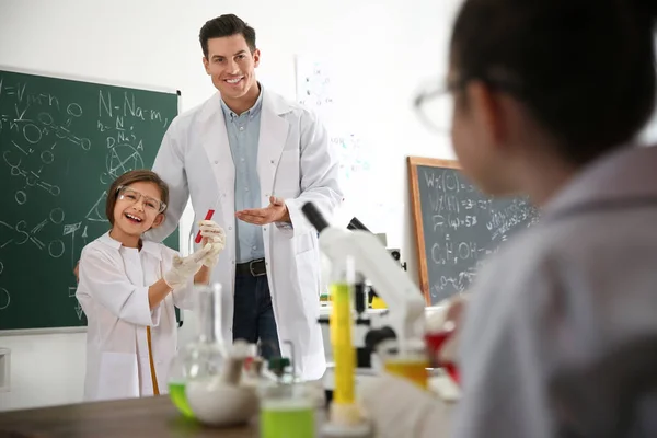 Teacher with pupil at chemistry lesson in classroom — ストック写真