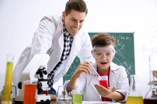 Tanár a tanulóval kísérletezik az asztalnál a kémia órán — Stock Fotó