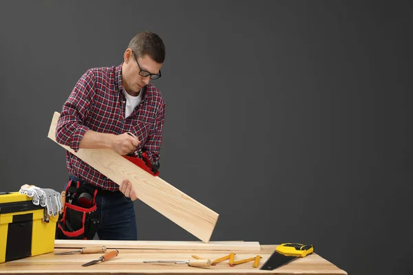 Knappe timmerman werkend met hout aan tafel op zwarte backgro — Stockfoto