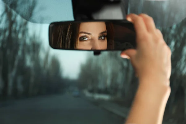 Jovem mulher ajustando retrovisor espelho no carro, close-up — Fotografia de Stock