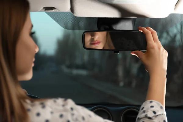 Jovem mulher ajustando retrovisor espelho no carro, close-up — Fotografia de Stock
