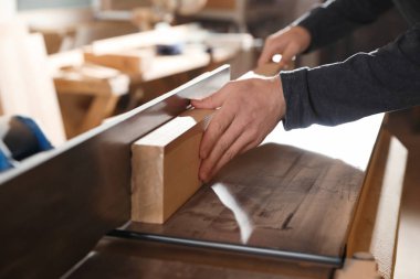 Professional carpenter working with surface planer in workshop, closeup