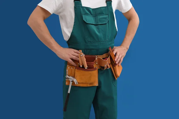 Carpenter with tool belt on blue background, closeup — Stock Photo, Image