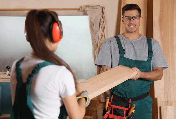 Профессиональные плотники с деревянной доской в мастерской — стоковое фото