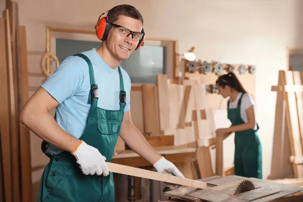Professionele timmerman met houten plank in werkplaats — Stockfoto
