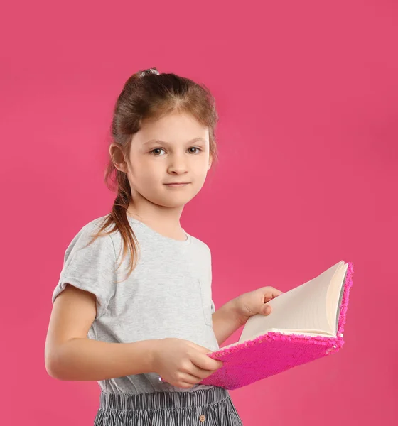 Niña con libro sobre fondo rosa — Foto de Stock