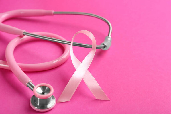 Pink ribbon and stethoscope on color background, closeup. Breast