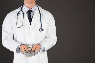 Siyah arka planda rüşvetle kelepçelenmiş bir doktor, yakın plan. Cor