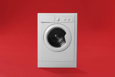 Kırmızı arka planda modern çamaşır makinesi. Çamaşır günü