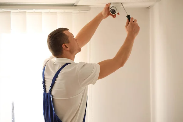 Técnico de instalação de câmera cctv no teto dentro de casa — Fotografia de Stock