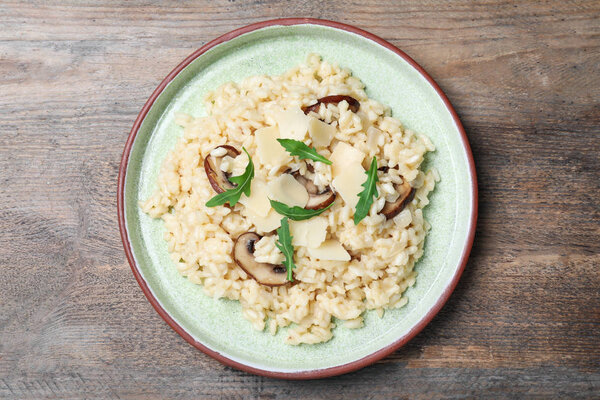 Delicious risotto with cheese and mushrooms on wooden table, top view