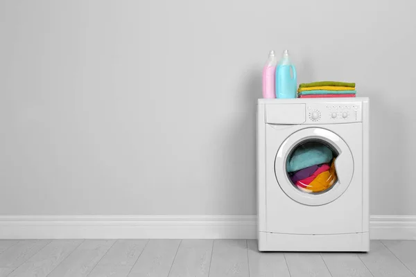 Modern washing machine with stack of towels and detergents near — 스톡 사진