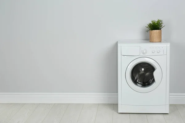 Modern washing machine with houseplant near white wall, space fo — 스톡 사진