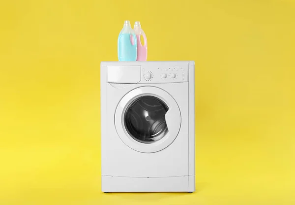 Modern washing machine with detergents on yellow background. Lau — Stock fotografie