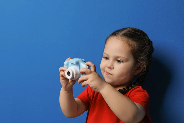 Pequeño fotógrafo tomando fotos con cámara de juguete en respaldo azul —  Fotos de Stock