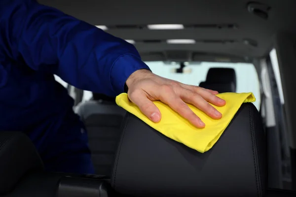 Car wash worker cleaning automobile interior, closeup