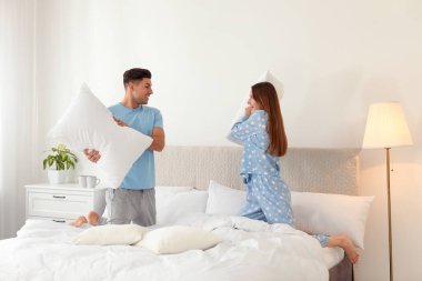 Mutlu çift yatak odasında yastık savaşı yapıyor.