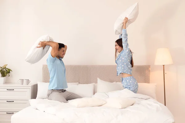 Счастливая пара, дерущаяся подушками в спальне — стоковое фото