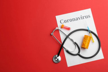 Kırmızı arka planda Coronavirus kelimesi, steteskop ve ilaç içeren düz kompozisyon. Metin için boşluk