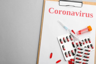 Kelime Coronavirus, test tüpü, şırınga ve ilaç içeren pano açık gri arka plan, üst görünüm
