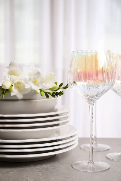 Set of glasses and dishes with flowers on light grey table — Stock Photo, Image