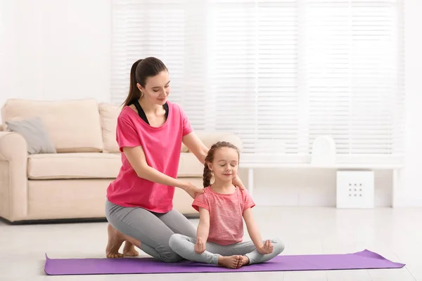 Jeune mère avec une petite fille pratiquant le yoga à la maison — Photo