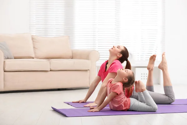 Young mother with little daughter practicing yoga at home — Stock Photo, Image