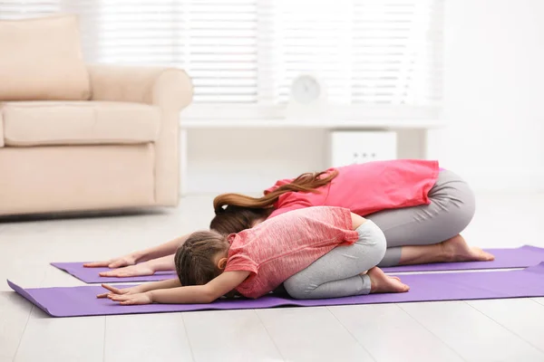 Jeune mère avec une petite fille pratiquant le yoga à la maison — Photo