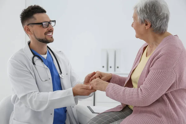 Doctor sosteniendo las manos de un paciente mayor en el consultorio —  Fotos de Stock