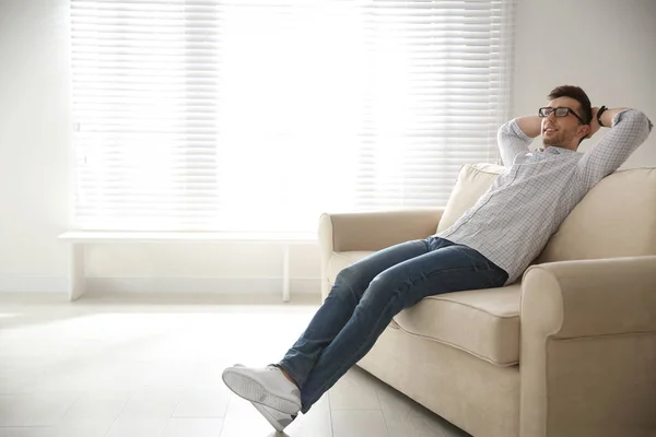 Mladý muž odpočívá na gauči u okna. Mezera pro text — Stock fotografie
