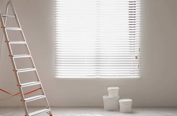 Stufenleiter und Eimer mit Farbe in der Nähe der Wand im Raum. Innenausbau — Stockfoto