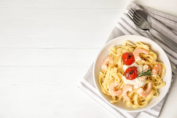 Delicious pasta with shrimps served on white wooden table, top view. Space for text