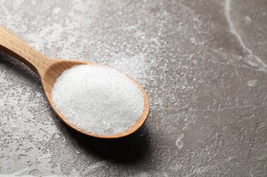 Mermer masada bir kaşık beyaz şeker, yakın plan. Metin için boşluk