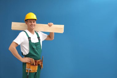 Handsome carpenter with wooden planks on blue background. Space 