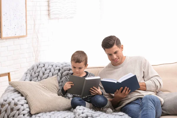 Far och hans son läser böcker hemma. Vintersemester — Stockfoto