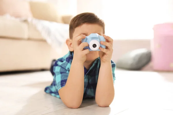 Маленький фотограф фотографирует с игрушечной камерой дома — стоковое фото