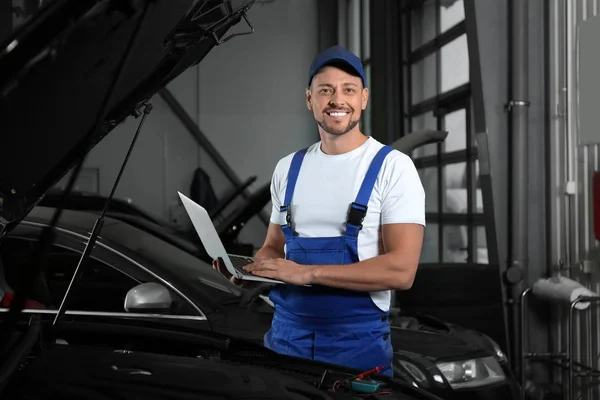 Mechanic with laptop doing car diagnostic at automobile repair s — Stok fotoğraf