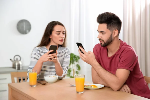 Mujer joven desconfiada mirando en el teléfono inteligente del novio en h — Foto de Stock