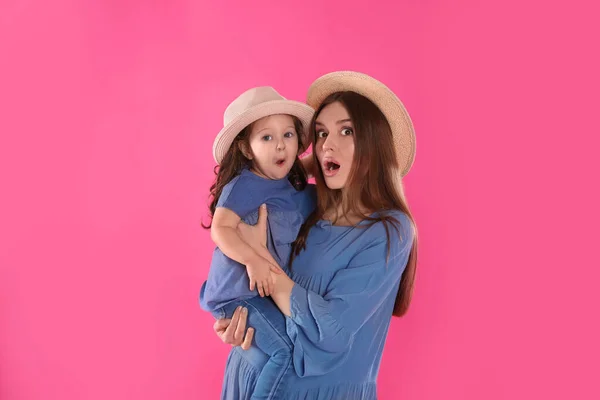 Emotional mother and little daughter with hats on pink backgroun — Stock Photo, Image