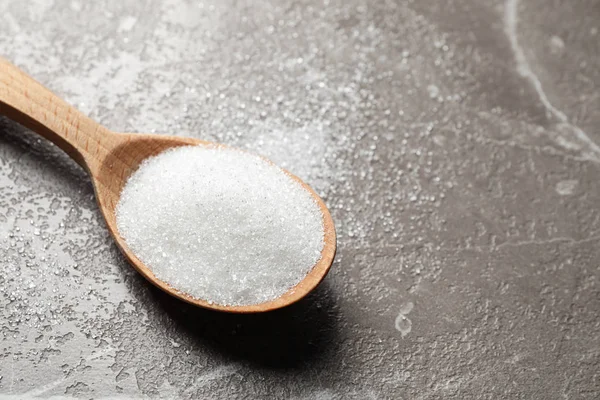 Cuchara de azúcar blanca en la mesa de mármol, primer plano. Espacio para texto — Foto de Stock