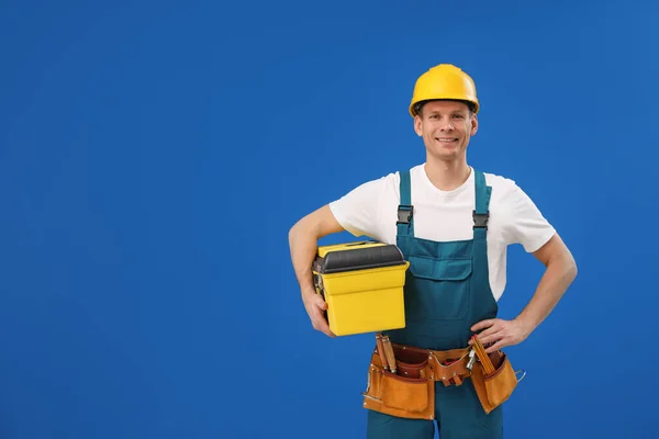 Knappe timmerman met gereedschapskist op blauwe achtergrond. Ruimte voor t — Stockfoto