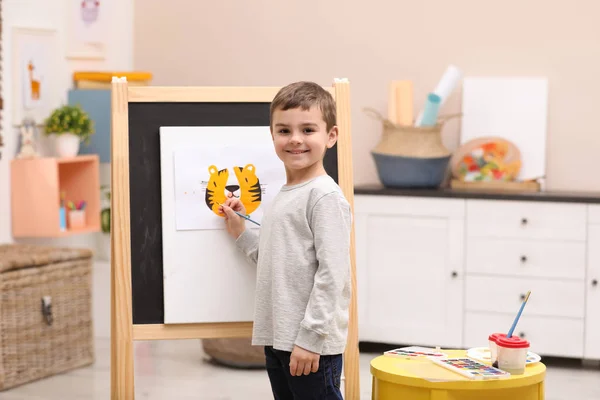 Little child painting on easel in room — ストック写真