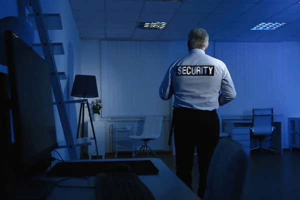 Professional security guard at work in dark office — Stock Photo, Image