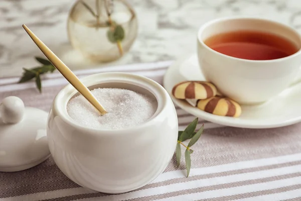 Granulált cukor tálban és aromás tea az asztalon — Stock Fotó