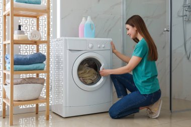 Banyodaki çamaşır makinesinin yanında bir kadın. Çamaşır günü