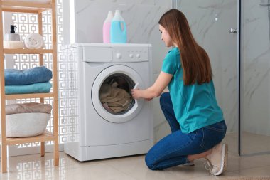 Banyodaki çamaşır makinesinin yanında bir kadın. Çamaşır günü