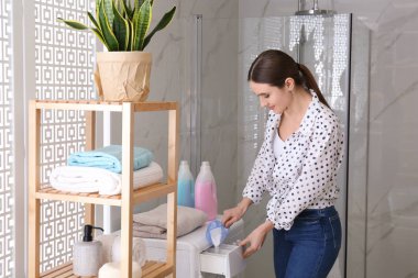 B 'deki çamaşır makinesi çekmecesine çamaşır deterjanı döken kadın.